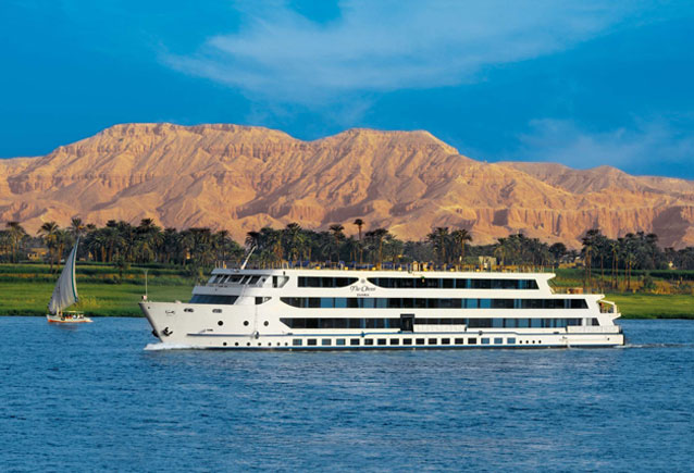 Modern white Nile River cruise ship sailing near Luxor, Egypt, framed by desert mountains, part of the Pride Adventures LGBTQ+ Egypt & the Nile group journey.