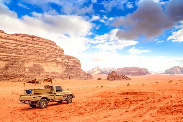 4x4 vehicle driving through the red sand desert and rock formations of Wadi Rum Jordan