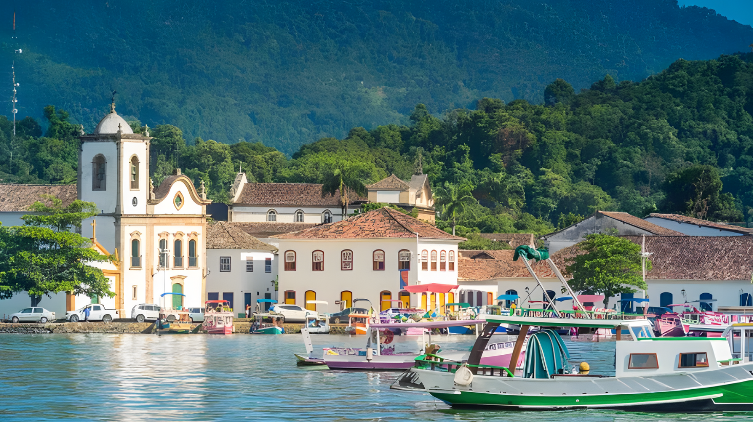 Colorful boats along the waterfront in Paraty Brazil with colonial buildings and lush green hills behind the town