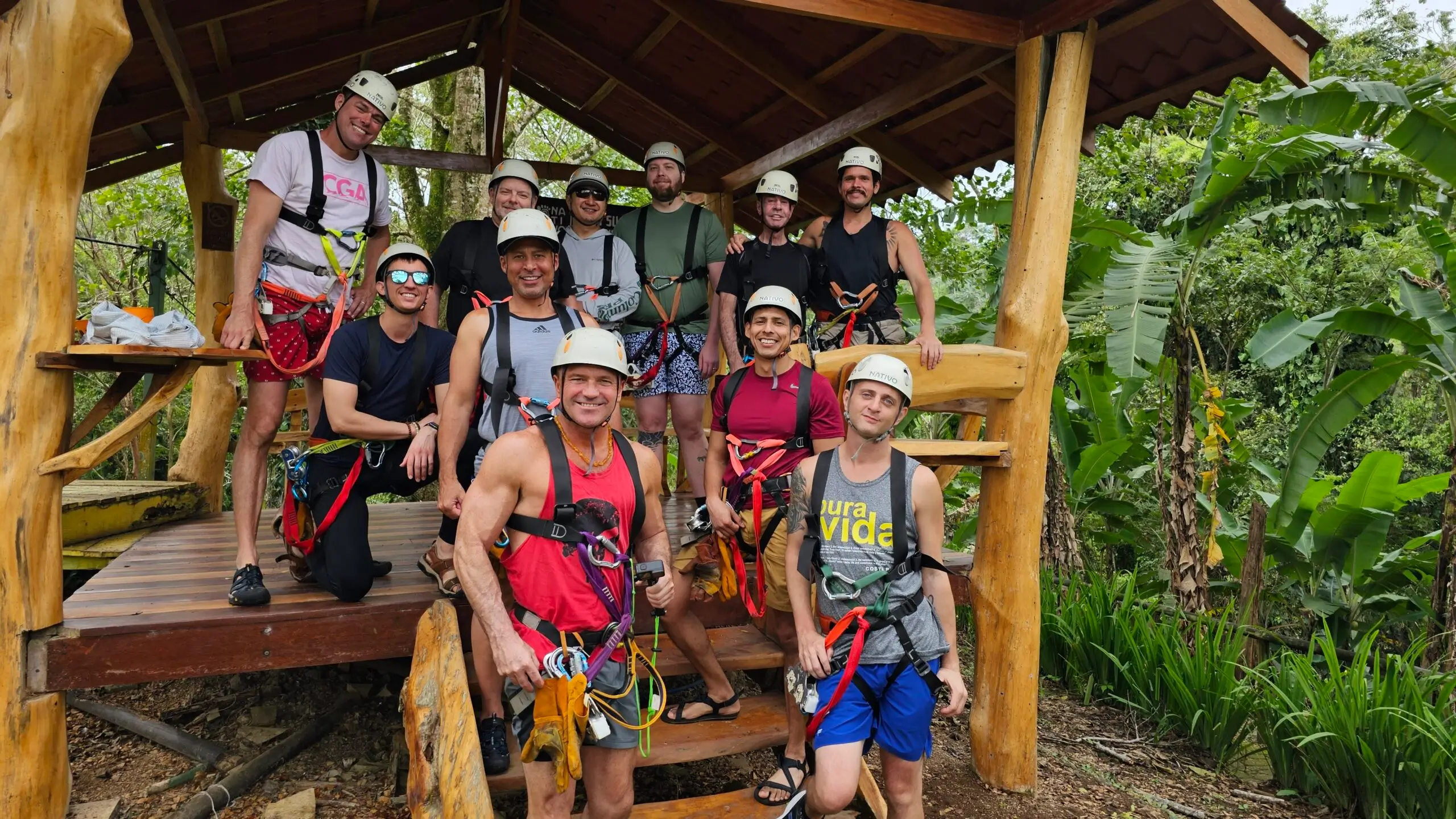LGBTQ+ travel group wearing helmets and harnesses for a zip line or canopy adventure activity in a tropical rainforest