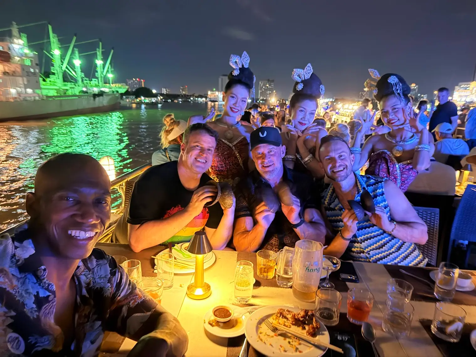 Gay men LGBTQ+ travelers enjoying dinner and entertainment at a waterfront venue in Thailand