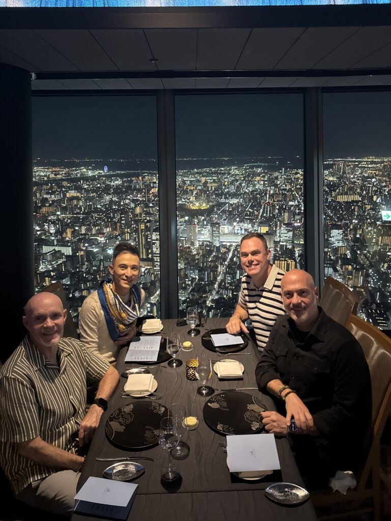 LGBTQ+ travel group enjoying dinner with panoramic views of Tokyo skyline at night