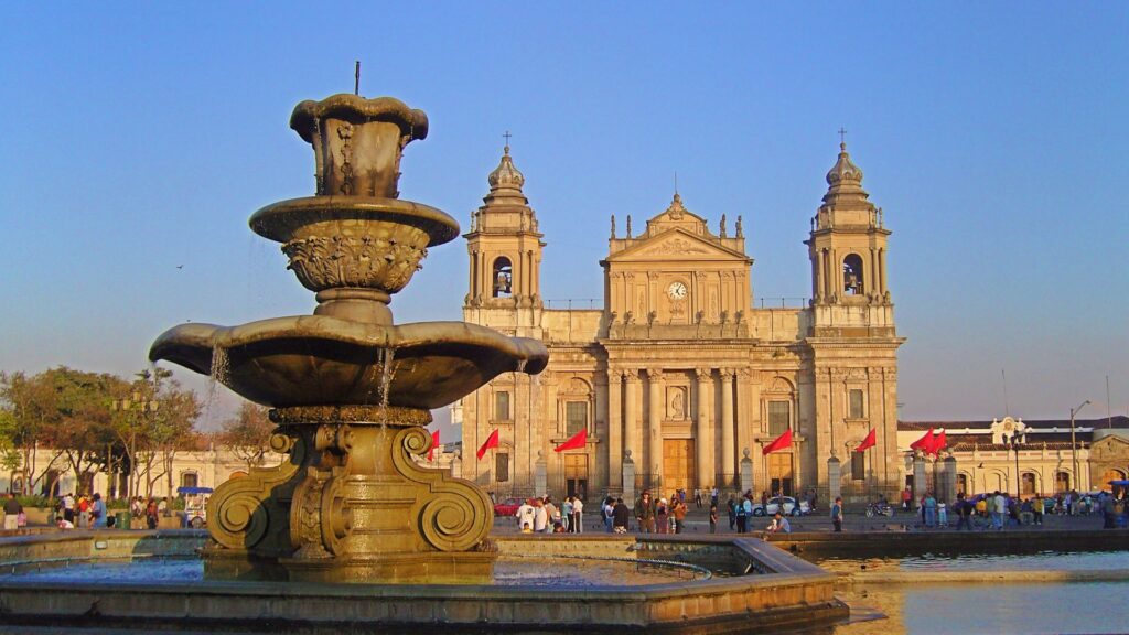 Historic Plaza Mayor fountain in Guatemala City with the Metropolitan Cathedral at golden hour