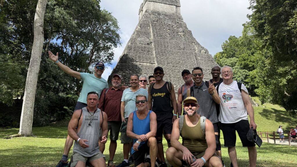 Group of travelers posing together in front of an ancient Maya pyramid at Tikal National Park, Guatemala