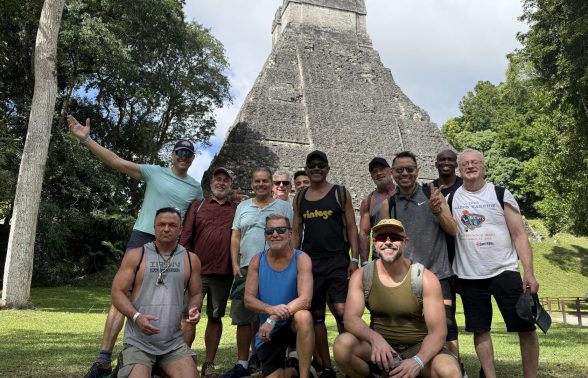 Group of travelers posing together in front of an ancient Maya pyramid at Tikal National Park, Guatemala