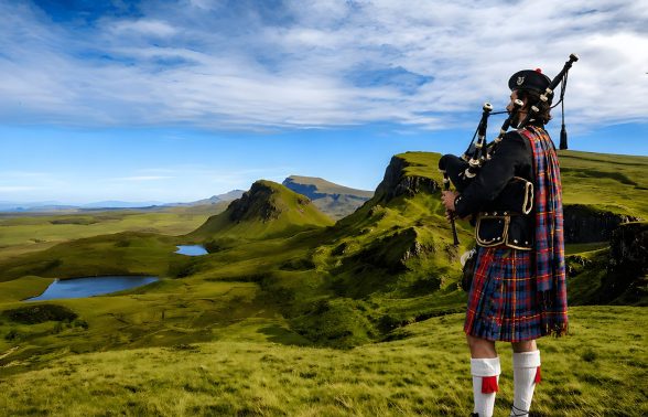 Scottish bagpiper overlooking the Isle of Skye Highlands on a Pride Adventures LGBTQ+ group trip in Scotland